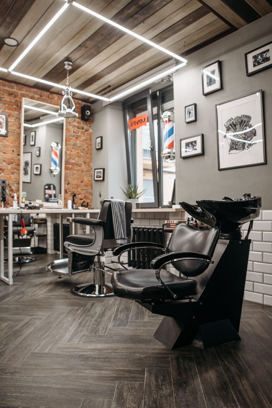 The shop interior — black leather chairs, exposed brick, and a barber pole reflected in the window